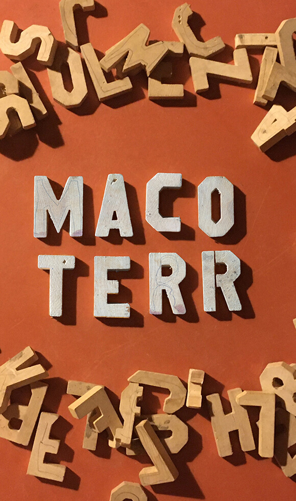 Pile of wooden block letters lying on an orange floor.